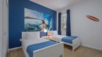 A room with two beds, a large ocean-themed painting, and a surfboard decal on the wall.