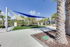 A paved walkway with a shaded area, palm trees, and a fenced park area. - Sr2684 - 4BR House With Pool Near Disney Parks (Kissimmee)
