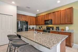 A modern kitchen with granite countertops, stainless steel appliances, and wooden cabinets. - Bv528 - 6BR House With Pool Near Disney (Kissimmee)