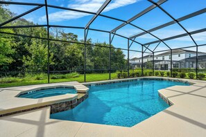 Ein Pool mit Glasüberdachung, umgeben von einer angelegten Grünfläche und Blick auf Wohnhäuser.