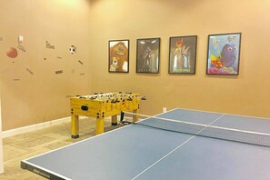 A room with a foosball table and a ping pong table, decorated with movie posters on the wall. - Bv528 - 6BR House With Pool Near Disney (Kissimmee)