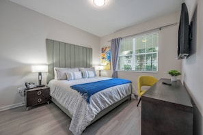 Une chambre à coucher moderne avec un lit, des tables de chevet, un bureau et une chaise.