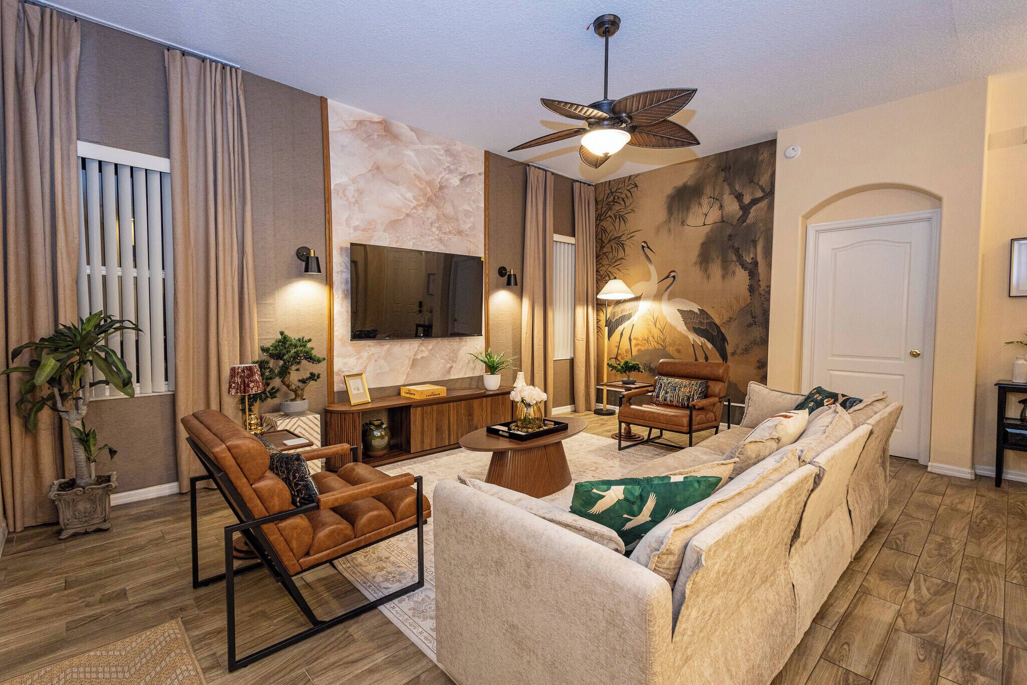 Un salon moderne comprenant un canapé, un fauteuil, une table basse et un ventilateur de plafond.