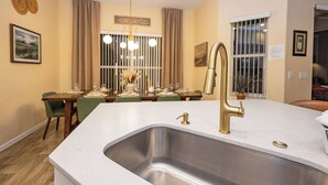A modern kitchen with a large island, stainless steel sink, and gold faucets. - Tu220 - 5BR House With Pool Near Disney Area (Davenport)