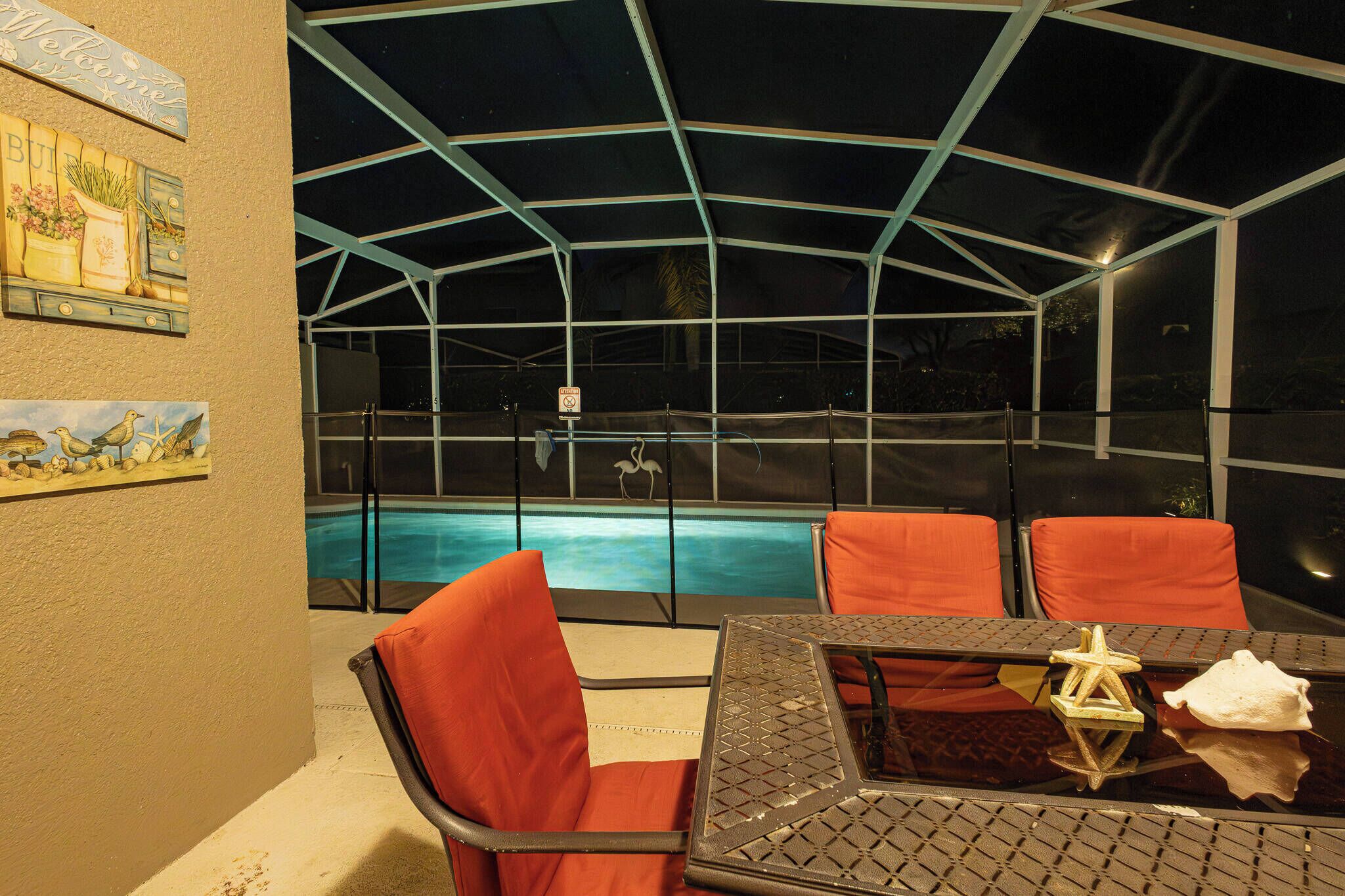 A covered outdoor area with a pool, orange chairs, and a table with a star decoration.