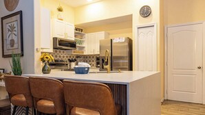 A modern kitchen with a central island, bar stools, and stainless steel appliances. - Tu220 - 5BR House With Pool Near Disney Area (Davenport)