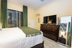 A bedroom with a bed, a dresser, a television, and a mirror. - Tu220 - 5BR House With Pool Near Disney Area (Davenport)