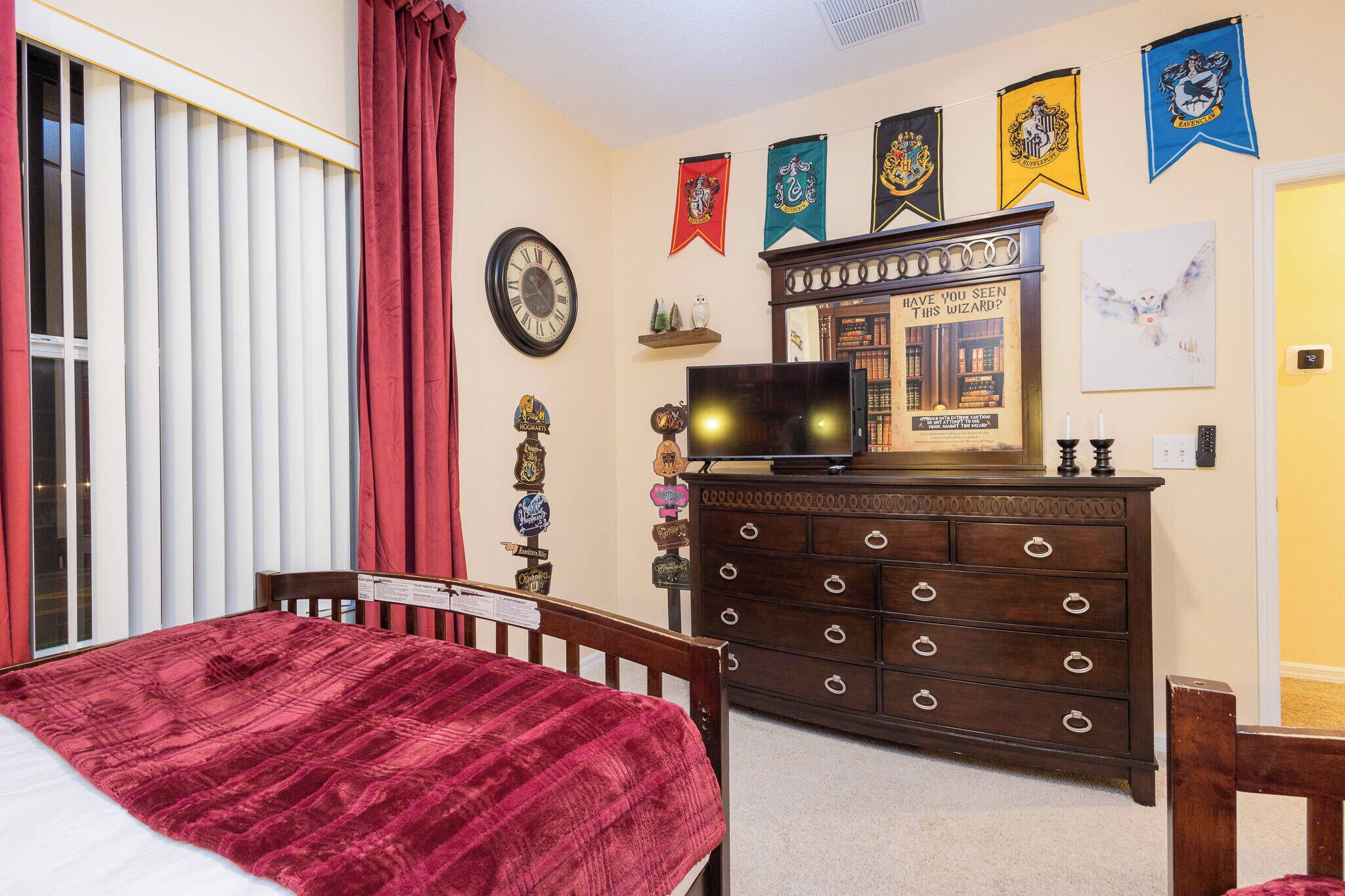 Une chambre à coucher comprenant un lit, une commode et des éléments de décoration murale, notamment des drapeaux et une horloge.
