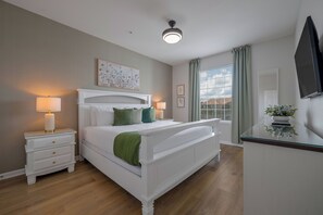 A bedroom with a white bed, bedside tables, a ceiling light, a window with curtains, and a wall-mounted TV. - Vc9-410 - 3BR Condo Near all Attractions (Orlando)