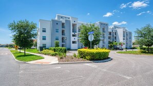 A multi-story residential building with balconies, a pedestrian crossing, and a stop sign. - Sl4751-208 - 3BR Apartment Near Disney (Kissimmee)