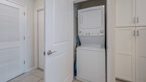A laundry room with a washer and dryer, a door, and a cabinet. - Sl4751-208 - 3BR Apartment Near Disney (Kissimmee)