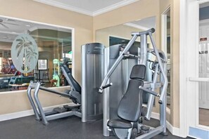 A gym with exercise equipment, a glass wall with a palm tree decoration, and a door leading to another room. - Wh7712 - 6BR House w/ Resort Access Near Disney (Kissimmee)