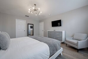 Ein Schlafzimmer mit Bett, Fernseher, Sessel und Kommode.