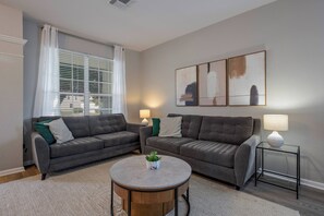 A living room with two grey sofas, a round coffee table with a plant, and a side table with a lamp. - Wh7712 - 6BR House w/ Resort Access Near Disney (Kissimmee)