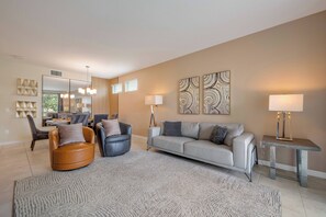 A modern living room with a sofa, armchairs, a coffee table, and a dining area with chairs and a table. - Sl4731-101 - 3BR Modern Apartment Storey Lake (Kissimmee)