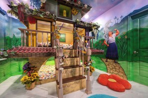 Ein Zimmer mit einer Holztreppe, einem Bett mit floralem Bettbezug und einem Wandbild einer Frau auf einer Wiese.