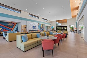 Eine großzügige Lobby mit modernem Design, ausgestattet mit einer geräumigen Sitzecke, bequemen Sofas und Sesseln, einem zentralen Couchtisch und einem großen Fenster für natürliches Licht.