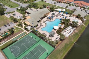 Ein Luftbild eines Resorts mit Schwimmbad, Tennisplätzen und Parkplatz.