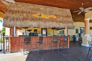 Un espace bar doté d’un toit de chaume, de tabourets et d’une enseigne sur laquelle on peut lire « LANDSHARK ».