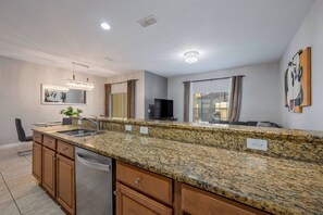 Eine moderne Küche mit Granit-Arbeitsplatten, Edelstahlgeräten und einem integrierten Geschirrspüler.