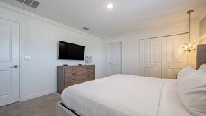 Un dormitorio con cama, cómoda, televisor y armario.