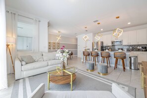 Un salon moderne avec un canapé, une table basse et des tabourets de bar.