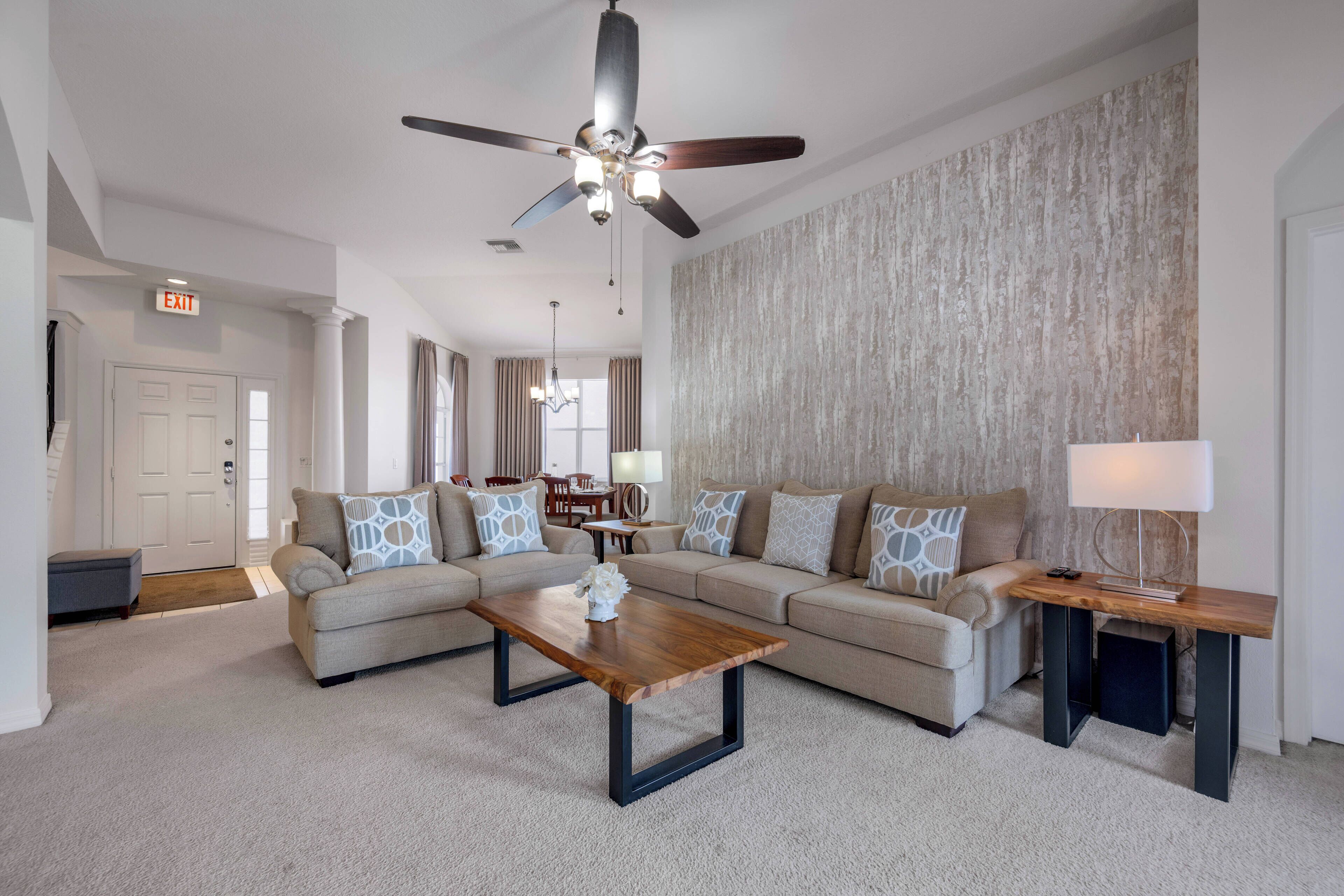 A living room with a sofa, coffee table, and a ceiling fan.