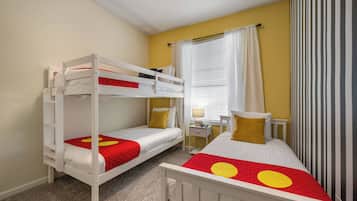 Una habitación con literas, un escritorio, una silla y un ventanal con cortinas.