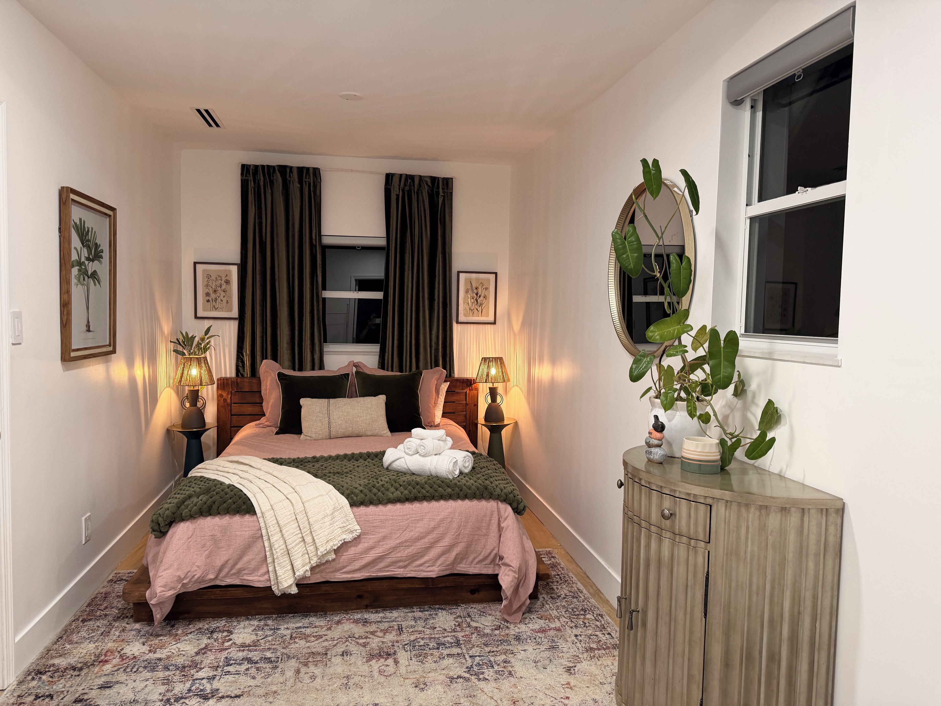 Une chambre à coucher avec un lit, des lampes de chevet, une commode, une fenêtre et un miroir.