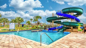 Un parque acuático con piscina, toboganes y palmeras.