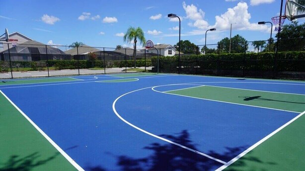 An outdoor basketball court with a blue and green surface, surrounded by a fence and trees. - Wp302 - 2BR Condo Near Walt Disney World (Kissimmee)