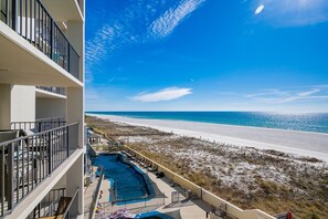 Ein Hotelbalkon mit Blick auf einen Strand und ein Schwimmbad.