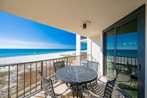A balcony with a round table and chairs, overlooking a beach. - Phoenix Iii 3033 1 Bedroom Condo (Orange Beach)