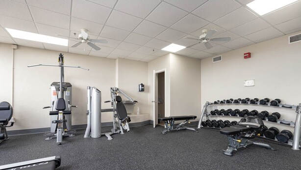 Ett gym med träningsutrustning, löpband och ett ställ med hantlar.