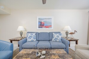 A living room with a sofa, two side tables with lamps, a coffee table with decorative items, and a painting on the wall. - Phoenix Iii 3085 1 Bedroom Condo (Orange Beach)