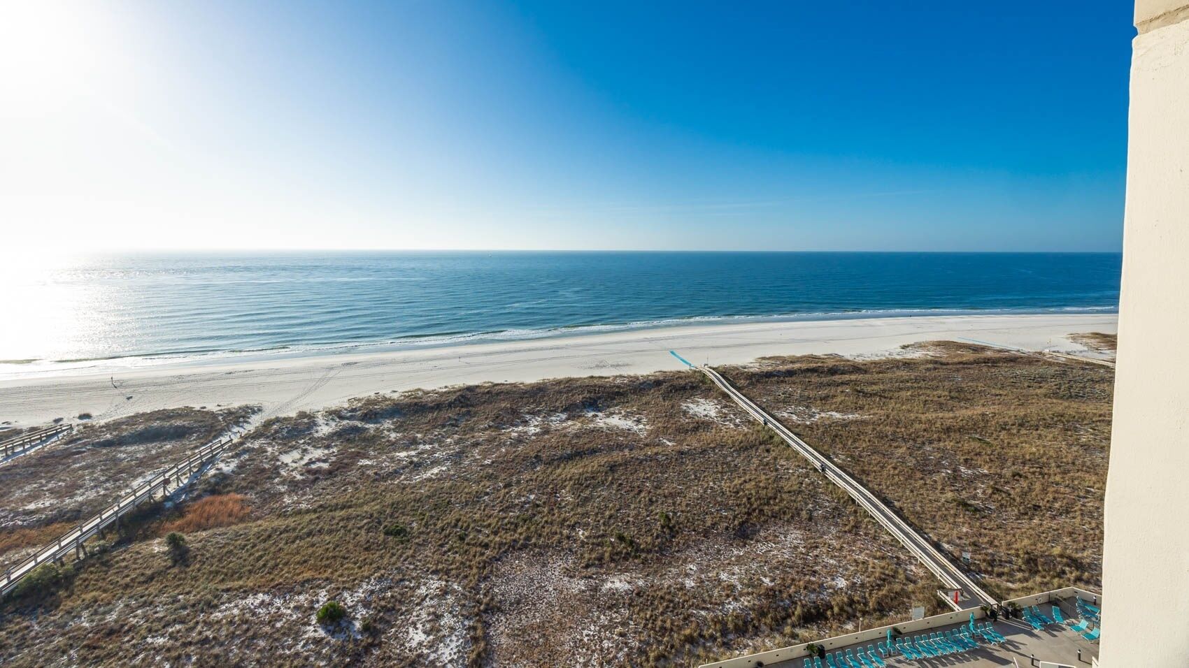A coastal landscape with a beach, grassy terrain, and a clear sky.