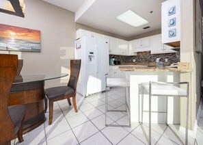 A modern kitchen with white cabinets, a granite countertop, and a built-in oven. - Phoenix Vii 71514 1 Bedroom Condo (Orange Beach)
