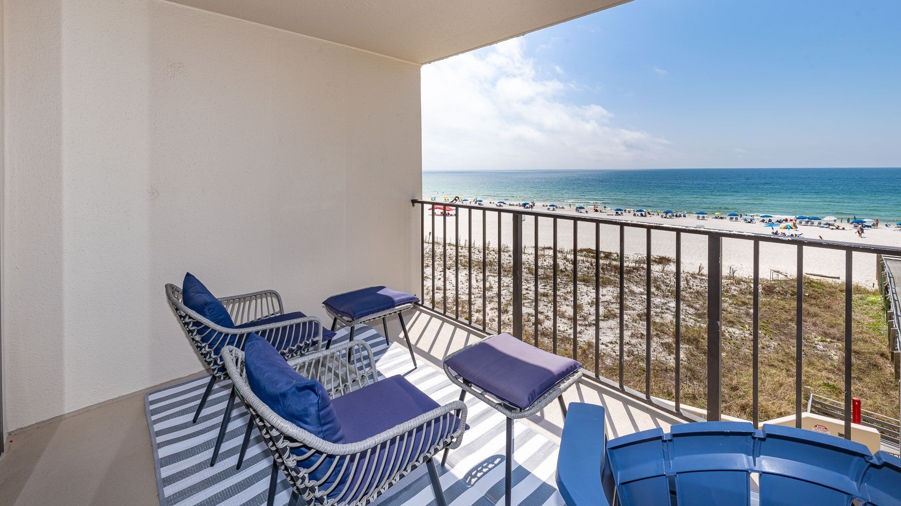 Ein Balkon mit Korbmöbeln und Blick auf einen Strand.