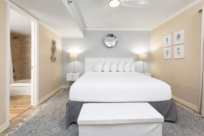 A bedroom with a large bed, bedside lamps, a round mirror, and a door leading to a bathroom. - Phoenix Iii 3035 1 Bedroom Condo (Orange Beach)