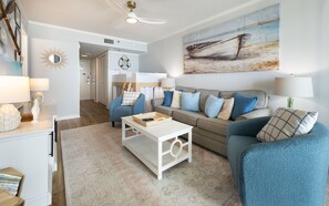 A modern living room with a sofa, armchairs, and a coffee table. There is a painting on the wall and a ceiling fan. - Phoenix Iii 3035 1 Bedroom Condo (Orange Beach)