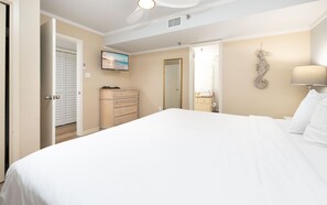A hotel room with a bed, a dresser, a mirror, a television, and a ceiling fan. - Phoenix Iii 3035 1 Bedroom Condo (Orange Beach)