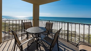 Ein Balkon mit Tisch und Stühlen mit Blick auf einen Strand.