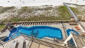 Ein Swimmingpool mit Liegefläche und Blick auf den Strand.