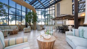 A spacious indoor area with large windows, comfortable seating, and a central coffee table.