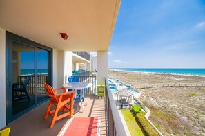 A balcony with a table and chairs, a pool area, and a view of the beach and ocean. - Phoenix Vii 7302 1 Bedroom Condo (Orange Beach)