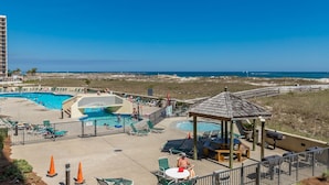 A resort with a swimming pool, lounge chairs, and a gazebo overlooking a beach. - Phoenix Vii 7103 3 Bedroom Condo (Orange Beach)