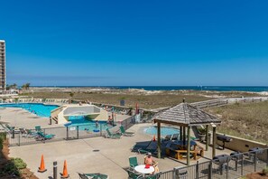 A resort with a swimming pool, lounge chairs, and a gazebo overlooking a beach. - Phoenix Vii 7103 3 Bedroom Condo (Orange Beach)