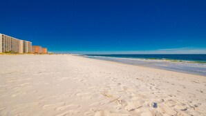 En strand med vit sand och en klarblå himmel.