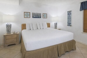 A bedroom with a large bed, two bedside tables, a nightstand, and wall decorations. - Phoenix Iii 3013 1 Bedroom Condo (Orange Beach)
