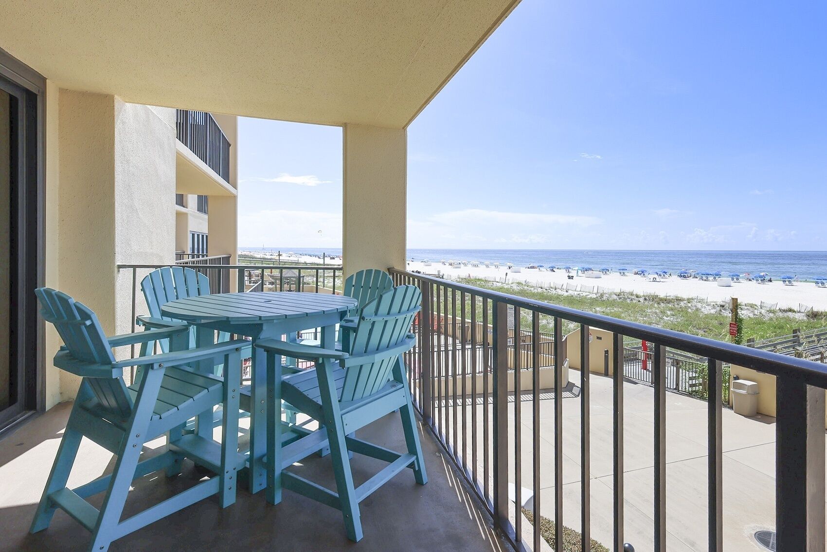 Ein Balkon mit Tisch und Stühlen mit Blick auf einen Strand.
